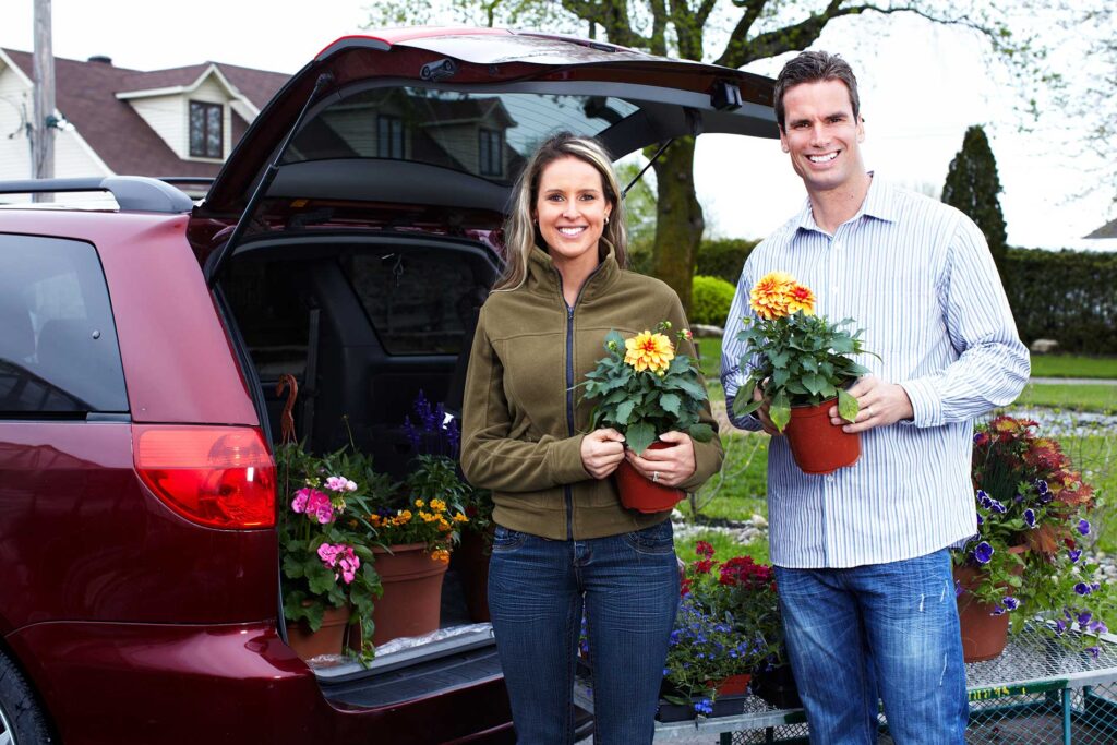 couple holding flowers outside of their car